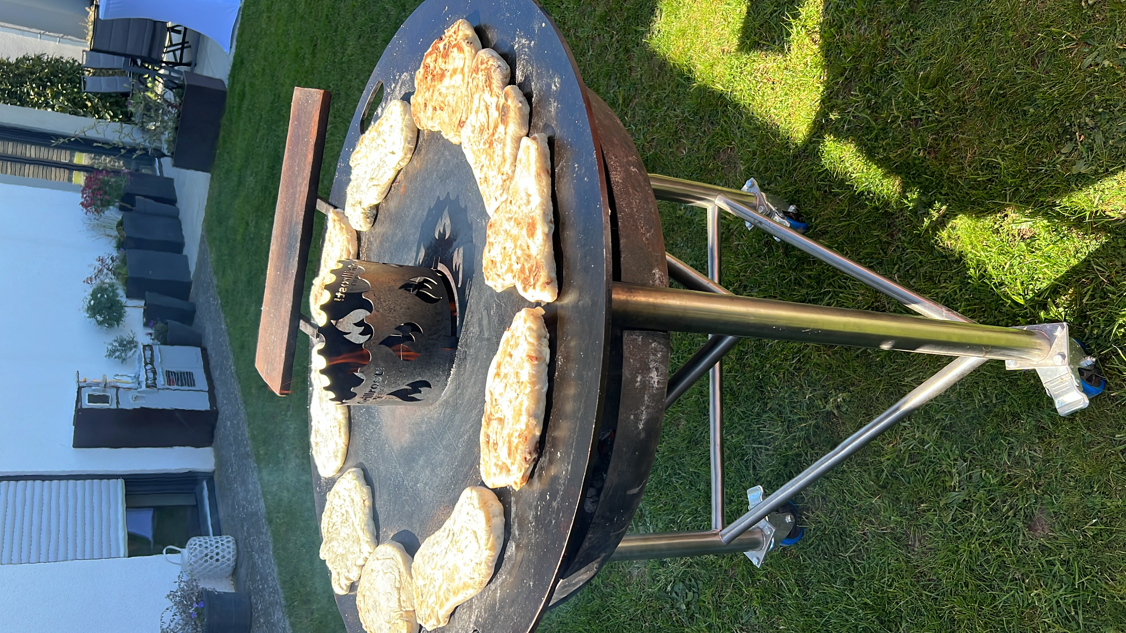 Frisches Fladenbrot brutzelt auf der Feuerplatte beim rustikalen Grillbuffet