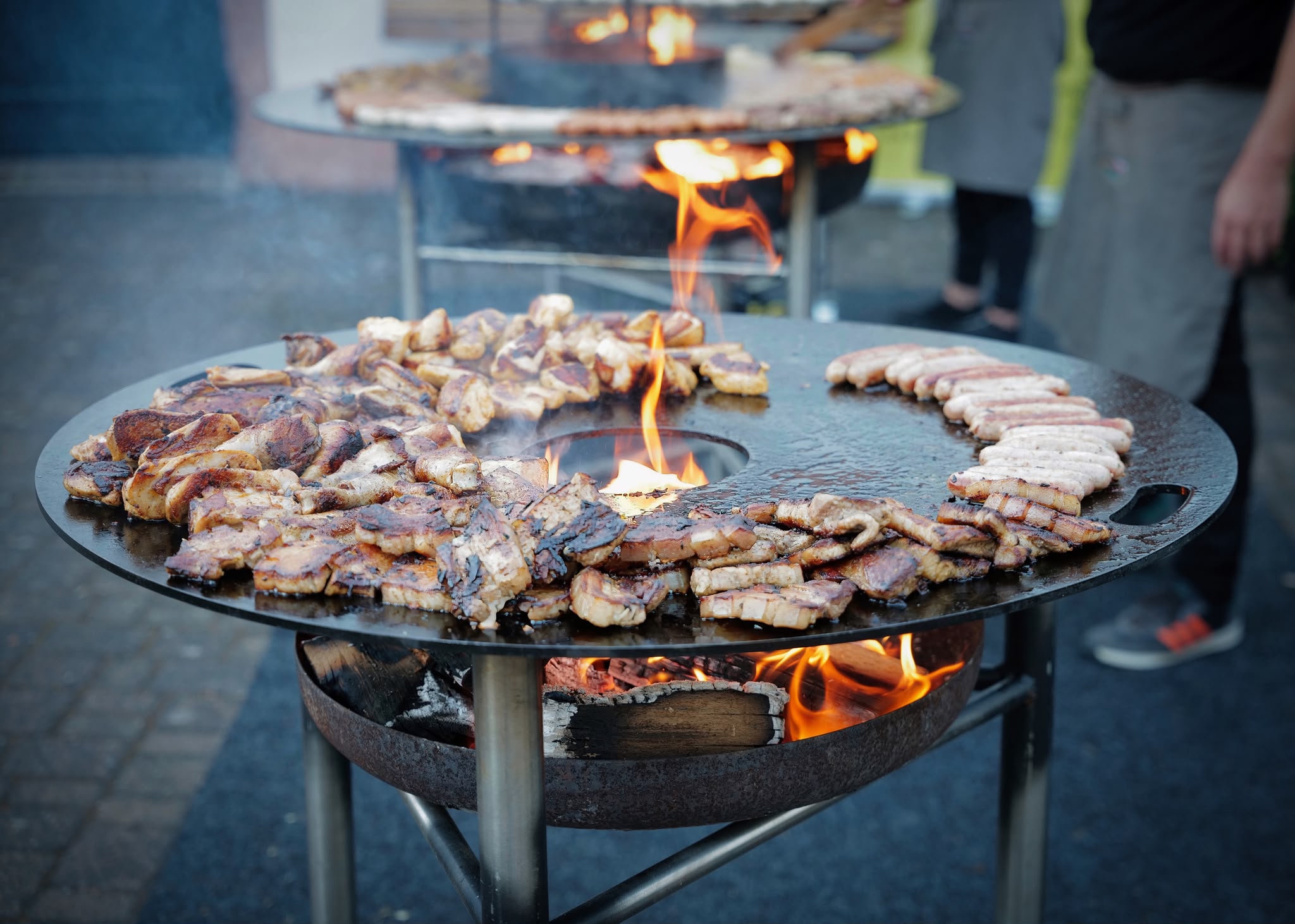 Rustikales Grillbuffet mit Bratwürsten, Fleisch und Speck auf der Feuerplatte